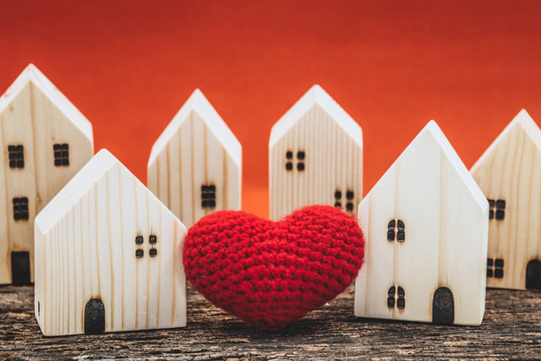 Любовное сердце между двумя моделями деревянного дома для того, чтобы остаться дома, любовь делится поддержкой вместе со здоровой концепцией хорошего сообщества. - Фото, изображение