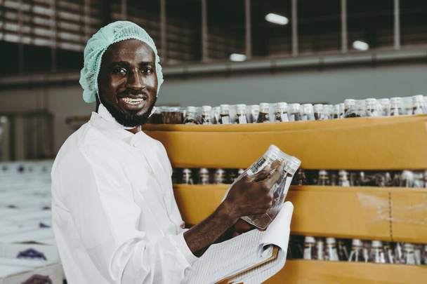 Fekete afrikai munkás dolgozik ipari gyári termékek ellenőrzése leltár készlet a raktárban. portré látszó kamera mosolygós. - Fotó, kép