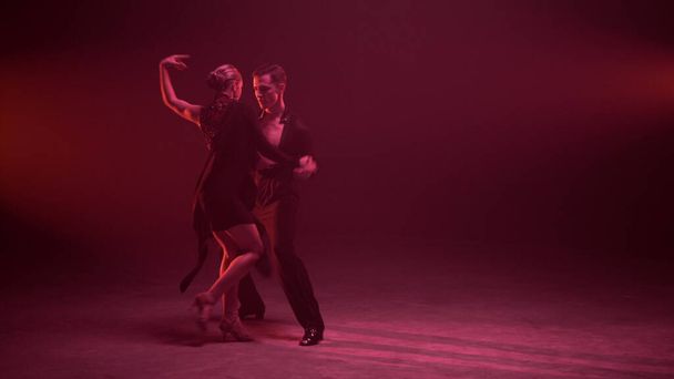 Professionelle Paare tanzen in voller Länge drinnen. Tänzer bewegen sich sinnlich. - Foto, Bild