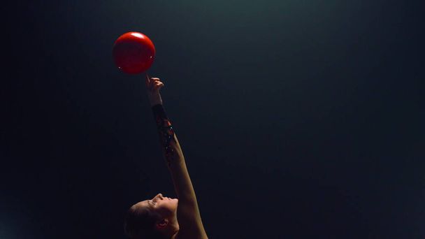 Wunderschöne Frau dreht Ball auf erhobenem Finger. Rhythmische Sportgymnastik. - Foto, Bild