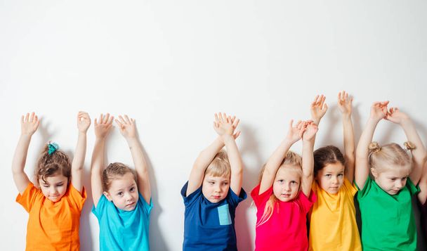 Children holding hands up on white wall background - Photo, Image