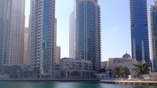 Dubai, Egyesült Arab Emírségek, 15.02.2021: Dubai Marina látkép Marina Canal, modern felhőkarcolók, luxus szállodák és az emberek sétálni és kerékpározni - Felvétel, videó