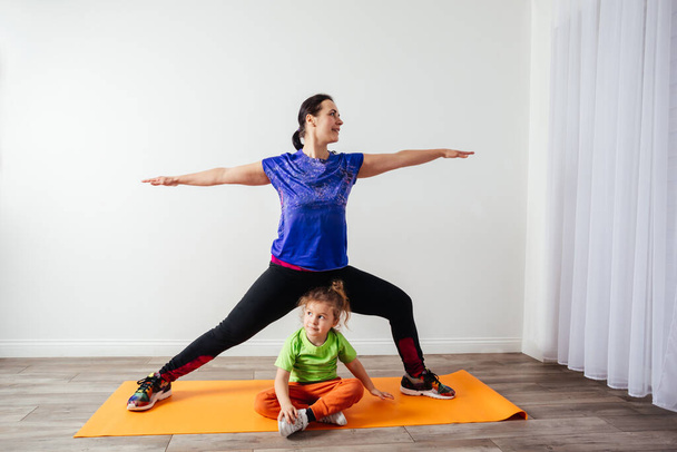 Cute little boy is bored while mother doing morning yoga - Foto, afbeelding