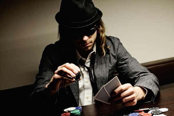Man with hat and glasses playing underground poker. - Фото, зображення
