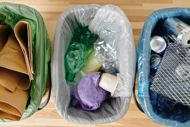Eine Gruppe verschiedener Arten von Müll in Plastiktüten auf einem Holztisch - Foto, Bild