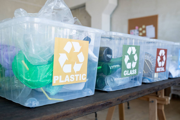 Fila de recipientes de plástico con donación reciclable sobre mesa negra - Foto, imagen