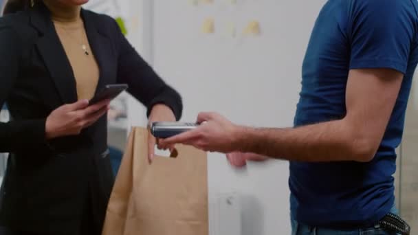 Lähikuva liikenainen maksaa noutoruoka lounas jotta älypuhelimella käyttäen POS - Materiaali, video