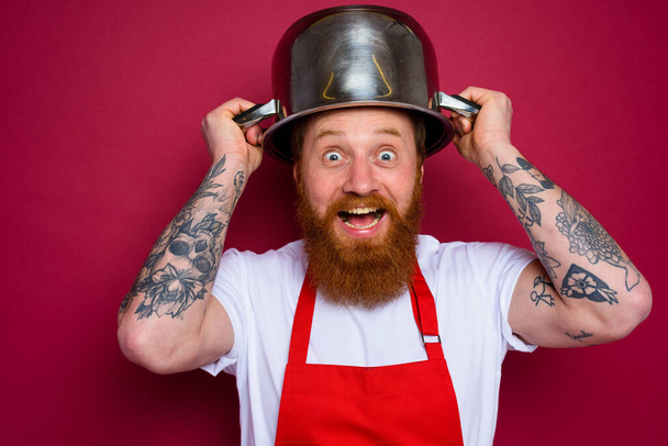 Щасливий шеф-кухар з бородою і червоним фартухом грає з горщиком
 - Фото, зображення