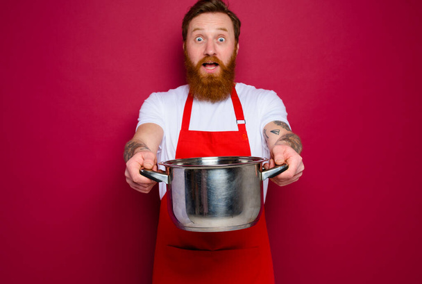 překvapený kuchař s plnovousem a červenou zástěrou je připraven vařit - Fotografie, Obrázek