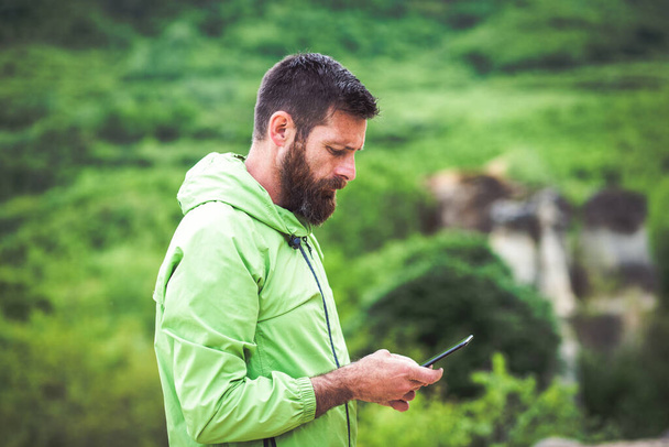 man trekking checking map on smartphone in summer scenery - Photo, Image