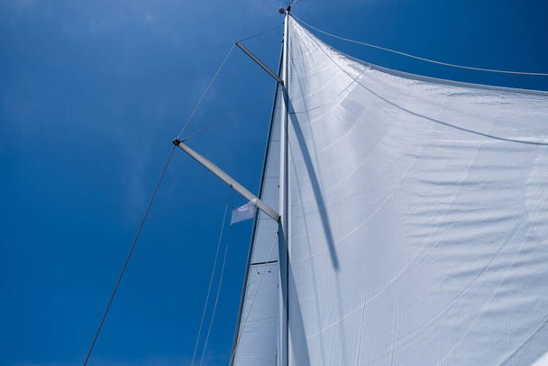 Yacht open sails on clear blue sky background. Sailing with the wind at Aegean sea, summer holidays at Greek islands. Looking up at the sky, low angle view - Fotó, kép