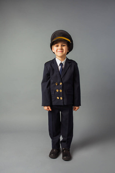 Boy dressed in a black pilot uniform stands at the gray background - 写真・画像