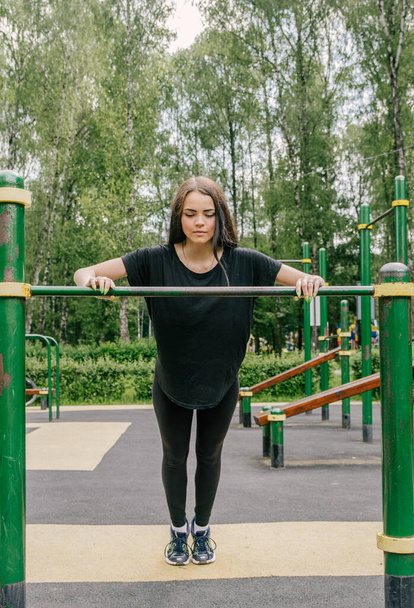 a girl in a black T-shirt and leggings shakes her hands from the - Фото, зображення