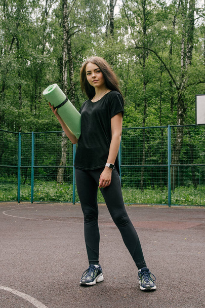 a girl in a black t-shirt and leggings stands on a sports basket - Fotó, kép