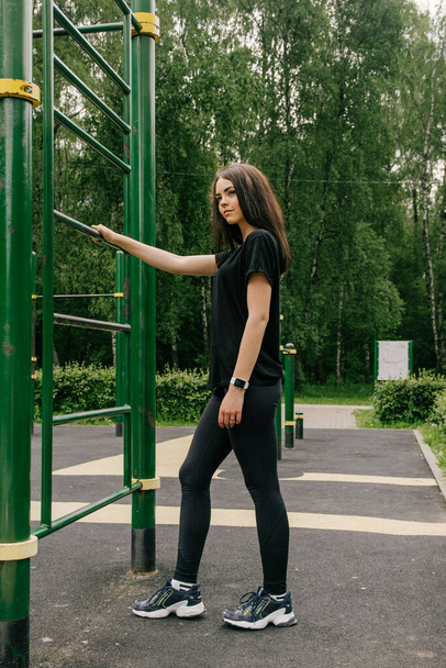 girl in a black t-shirt and leggings stretching on the stairs fo - Foto, Bild