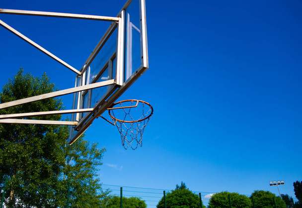 Basketbalový backboard s kroužkem na ulici na hřišti v pozadí oblohy - Fotografie, Obrázek