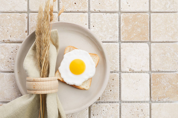 Stylish serving on a travertine mosaic background. Linen napkin and egg on plate. Top view - Photo, Image