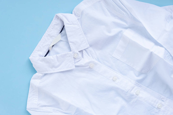 A white shirt with autumn leaves in the pocket. Back to school concept. The leaves are cut out of paper. Shirt on a blue background - Φωτογραφία, εικόνα