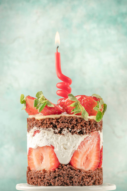 голый клубничный торт со свечой на день рождения на зеленом фоне с копировальным пространством - Фото, изображение