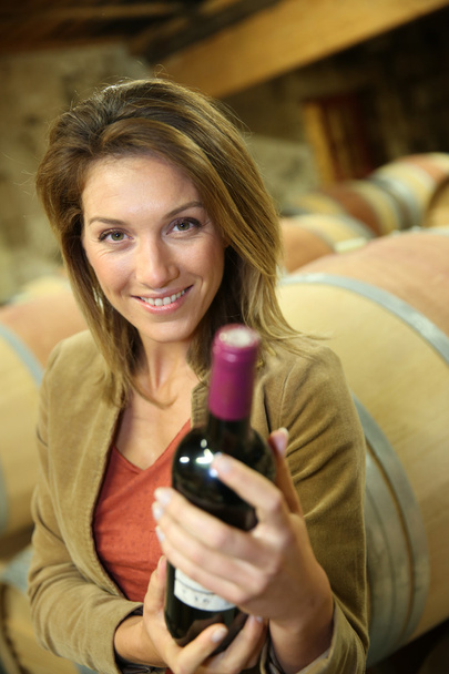 Woman holding bottle in  cellar - Foto, Bild