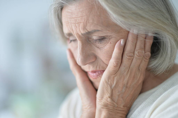 Close up portrait of sad senior woman with headache  - 写真・画像