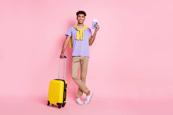 Full size photo of nice optimistic brunette guy stand with bag ticket wear t-shirt pants isolated on pink color background - 写真・画像
