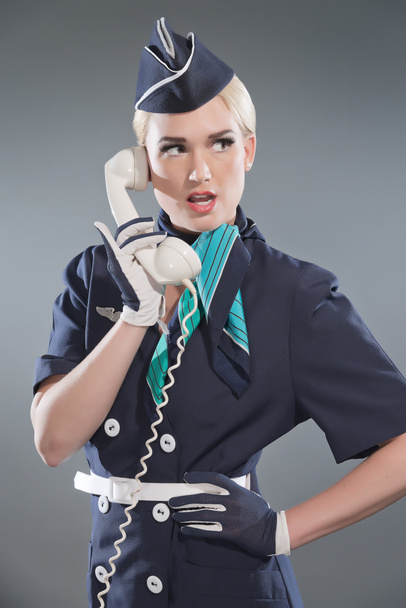 Soittaa retro blondi lentoemäntä yllään sininen puku. Tila valkoinen
 - Valokuva, kuva