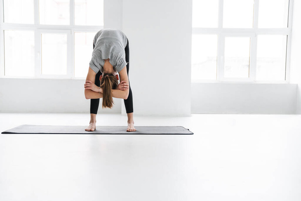 Здоровый привлекательный молодой женщины йоги растяжения на фитнес-мат в студии - Фото, изображение