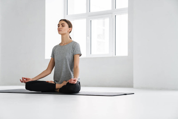 Attractive young woman practicing meditation in yoga studio - Foto, Imagem