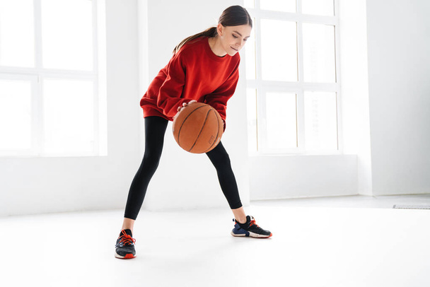 Athletic young sportswoman working out with basketball indoors - Foto, Bild
