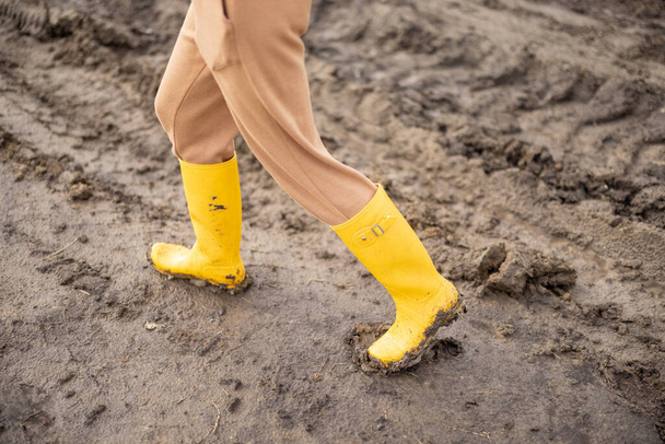 Piernas de agricultora en botas de goma amarillas caminando  - Foto, imagen