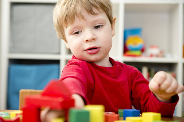 A young builder. kid building city from wooden blocks. Kids Play Room. Development and Construction Concept. - Foto, Imagem