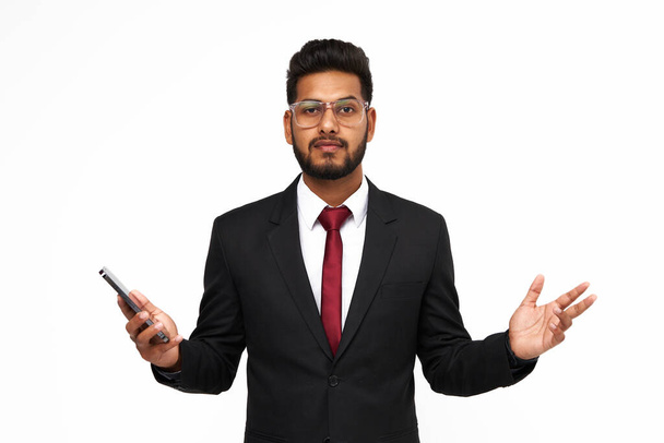 Portrait of surprised young indian business man with mobile phone on white isolated background. - Foto, afbeelding
