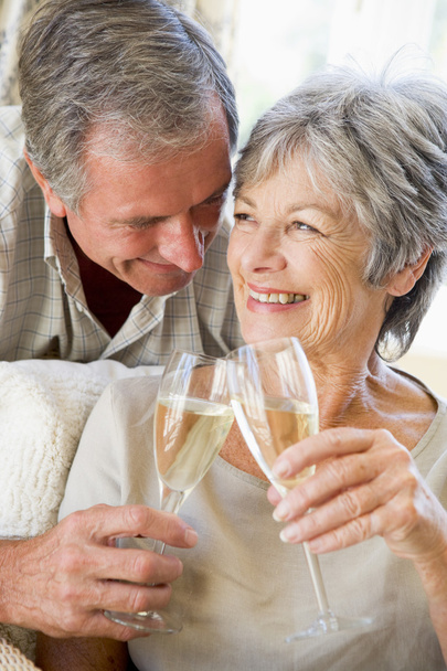 Couple in living room toasting champagne and smiling - Foto, imagen