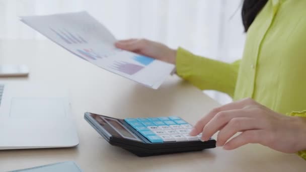 Closeup young asian business woman using calculator with calculate tax for chart and graph report of earning home, businesswoman working and plan budget of expense, finance and debt. - Πλάνα, βίντεο