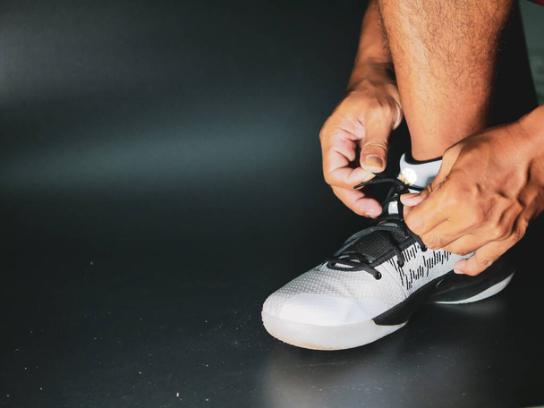 Zbliżenie sportowców wiążących paski na buty w ramach przygotowań do treningu po kryzysie COVID-19. - Zdjęcie, obraz