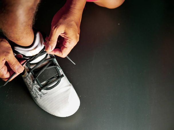 COVID-19 krizinden sonra antrenmana hazırlanmak için ayakkabı askısı bağlayan atletlerin yakın çekimleri. - Fotoğraf, Görsel