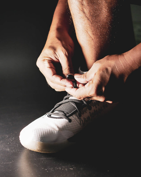 Gros plan des athlètes attachant des sangles de chaussures en préparation à l'entraînement après la crise COVID-19. - Photo, image