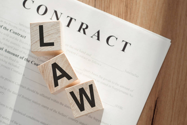 Word LAW on wooden cubes on contract documents background - Photo, Image