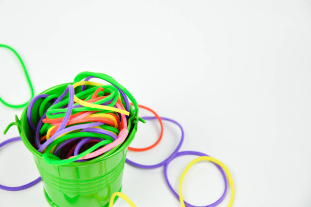The small green bucket is filled with a colorful rubber band isolated on white background. - Photo, Image