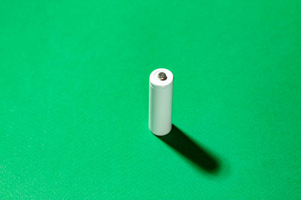 緑の背景に白いAA電池。テキスト用のスペース。充電式ニッケル水素電池のリサイクル. - 写真・画像