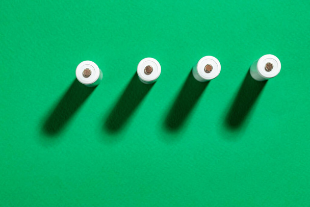 White AA batteries on a green background. Space for text. Recycling of rechargeable NiMH batteries. - Photo, Image
