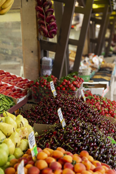 Fruit and berry stall on the market. Large assortment of fresh products. Side view. Vertical. - Foto, Imagen