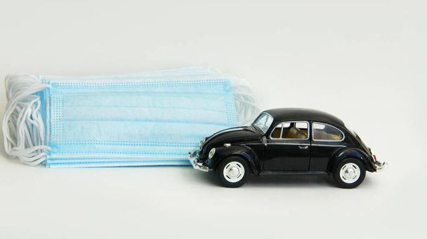 a black car next to the masks for protection from the corona virus.Travel safely.Protect your car from the corona virus.Travel in the car only in a protective mask from the virus - Zdjęcie, obraz
