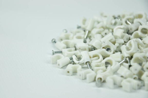 Plastic kabelklemmen met betonnen nagels geïsoleerd op witte achtergrond - Foto, afbeelding