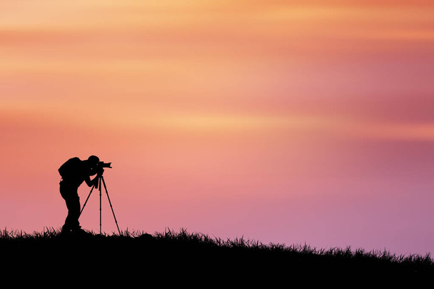 silhouette d'un photographe avec appareil photo sur fond de coucher de soleil - Photo, image