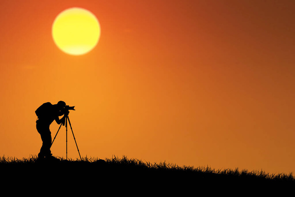 silhouette d'un photographe avec appareil photo sur fond de coucher de soleil - Photo, image