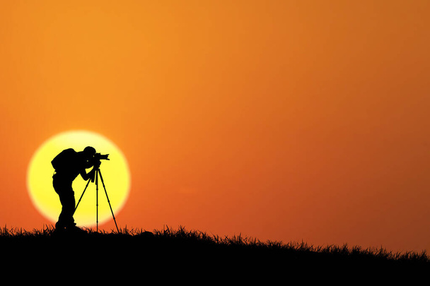 sylwetka fotografa z aparatem fotograficznym na tle zachodu słońca - Zdjęcie, obraz