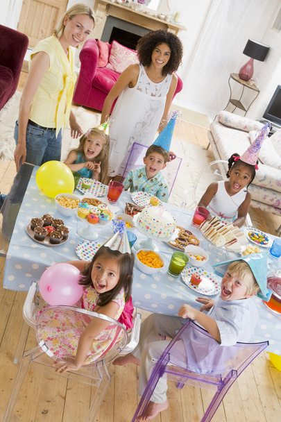 Young children at party with mothers sitting at table with food - Foto, Imagem