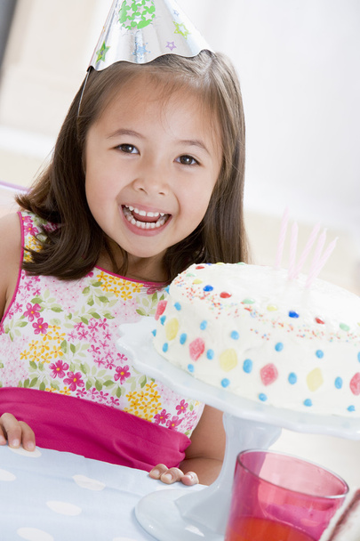 Young girl wearing party hat with birthday cake smiling - Фото, изображение